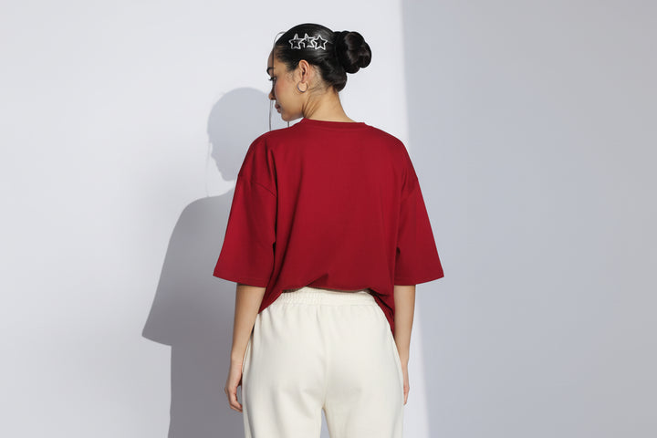 Person wearing a red oversized t-shirt against a white background